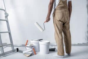 A man paints a white wall in home